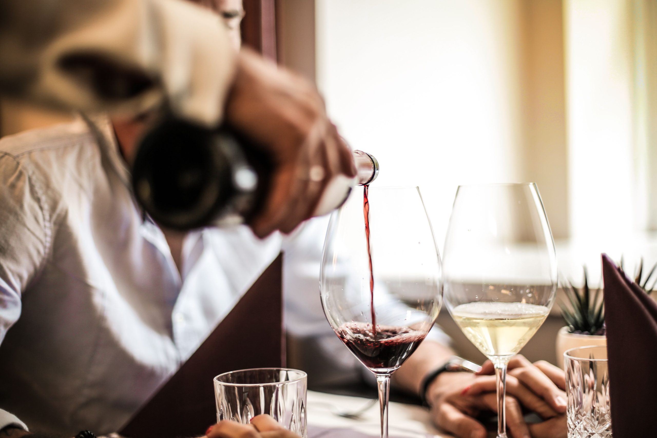 Garçom servindo vinho tinto em taça durante jantar